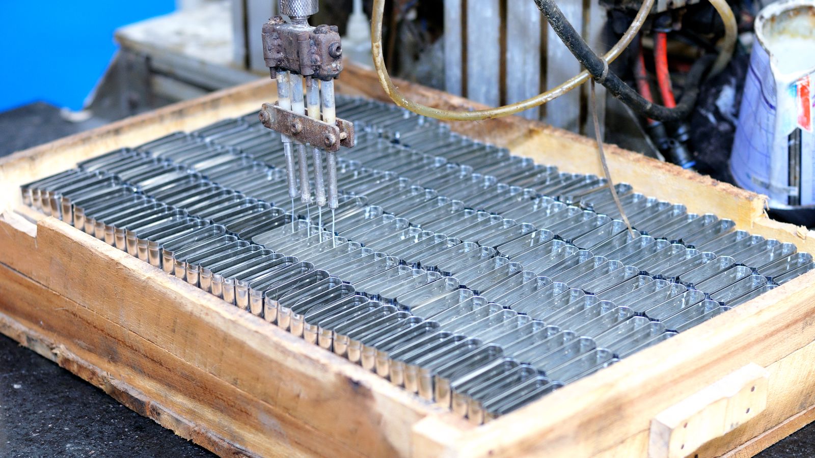 Metal finishing equipment processing rows of metal parts